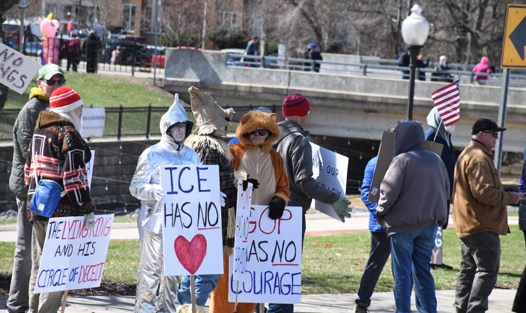 Demonstrators dressed as characters from "The Wizard of Oz" carry signs reading "ICE has no heart," "Trump has no brain," and "GOP has no courage."