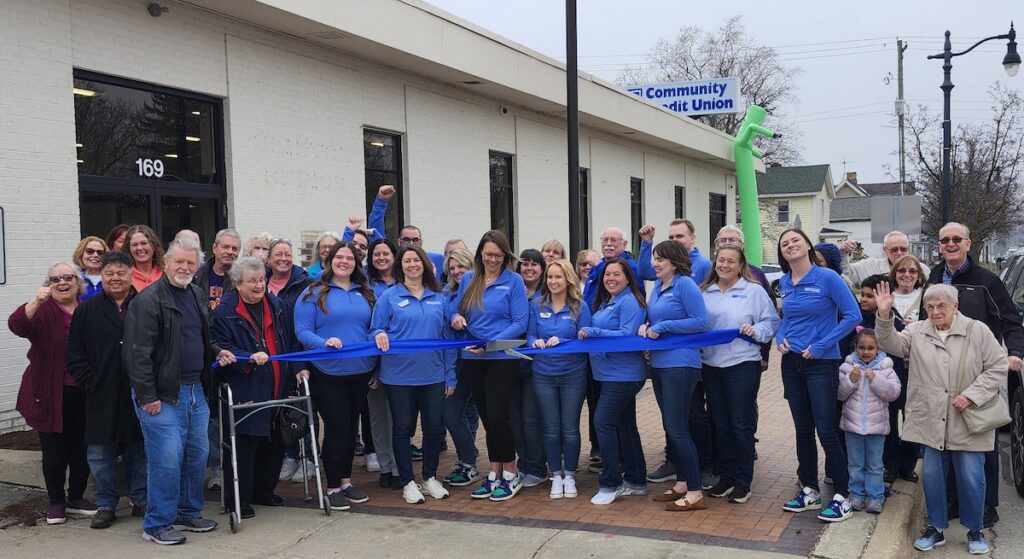 TLC Community Credit Union board chair Meredith Francis holds the ribbon as executive vice president Alycia Nichols wields the scissors at a March 21 ribbon cutting to open the credit union’s new branch in downtown Clinton. (Photo by Erik Gable)