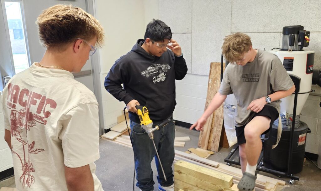 Adrian High School sophomore Zeke Smart, left, and juniors Jose Calieca and Nolan Wood work on one of the bases that students in Tony Aiken’s Introduction to Industrial Arts class are making for the cannons at Monument Park. (Photo by Erik Gable)