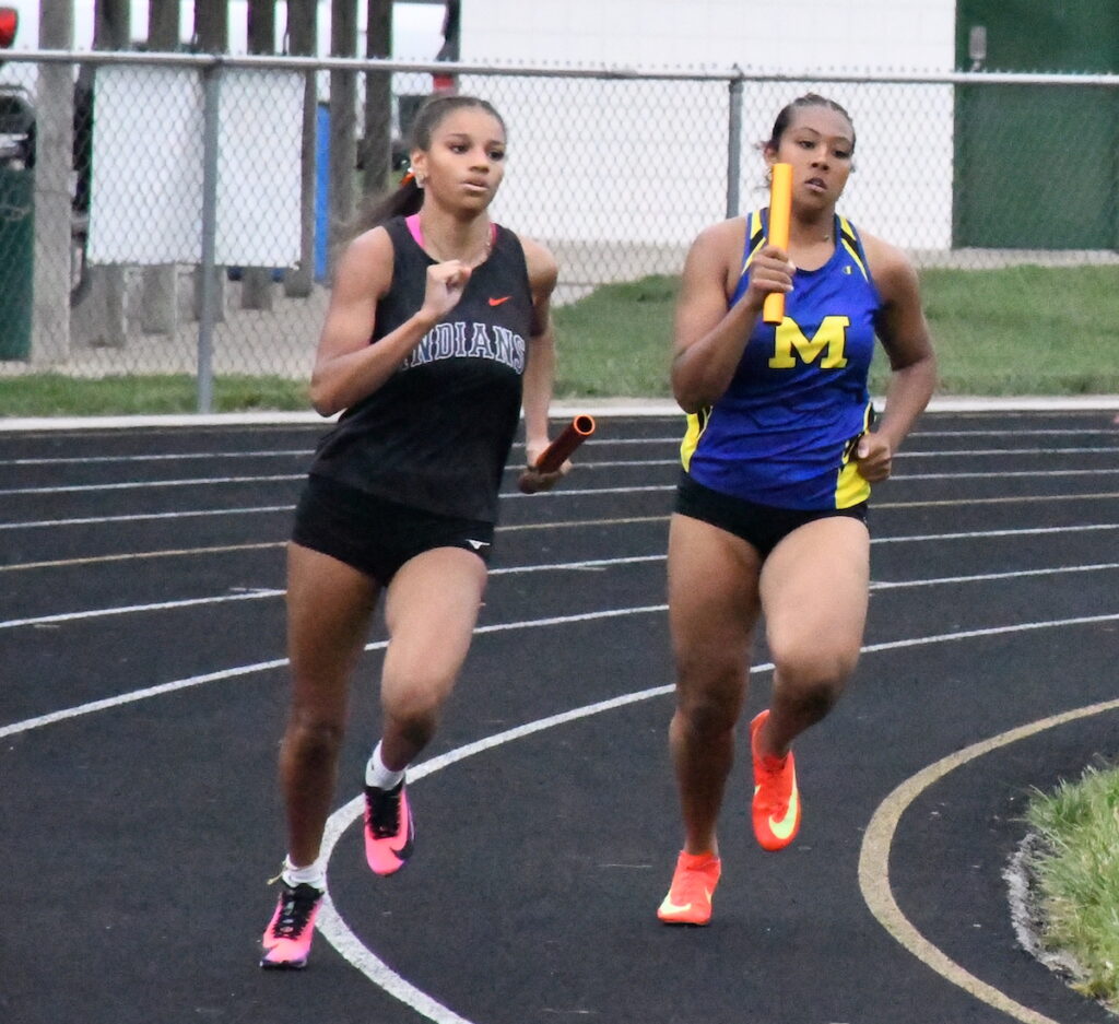 Holly Woods (Tecumseh) and Taelee LaVassaur (Madison) run in the final event of the evening, the girls 1,600-meter relay.