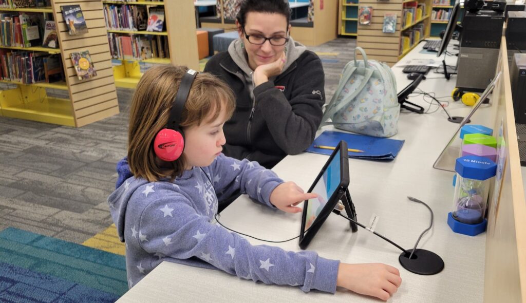 Allison Buehrer, 8, of Blissfield uses a tablet station with her mom, Rachel.