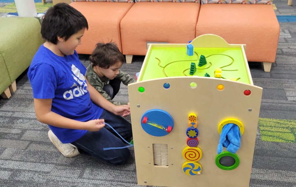 Ramiro Rosas, 11, of Adrian helps his younger brother Arthur, 4, with the play cube in the new Adrian District Library youth services department.