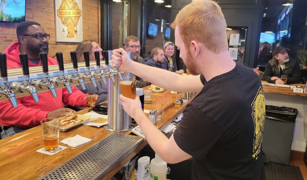 Carter Smith pours a beer at the Tecumseh Tavern during the Michigan game on Jan. 1.