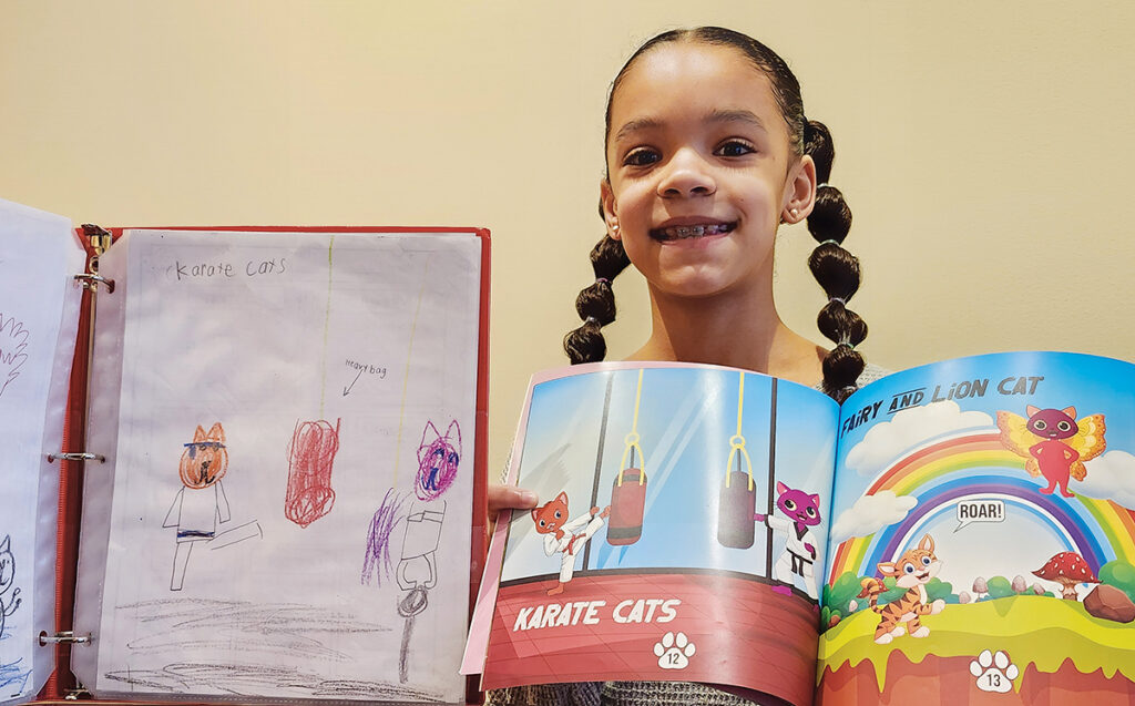 Evie Wallace, a third-grader at Madison Elementary School, shows one of the inventive cat drawings she made in first grade along with the book that her imagination inspired.