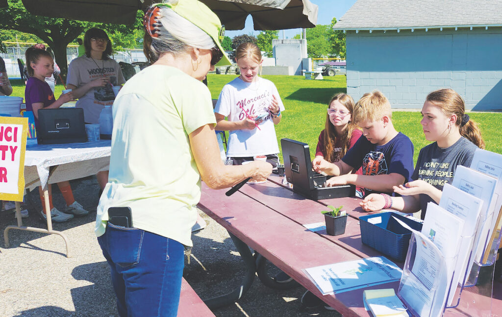 Aubrey Sandusky, Emma Overmeyer, Noah Zuvers and Heaven Ohlinger staff the checkout table at Morenci Area Schools’ student-run farmers market on May 18.