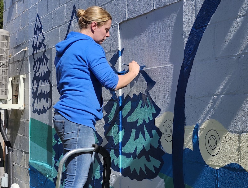 Holly Risch of Britton, owner of Inevitable Art LLC, works on painting the new Re-Bicycle Lenawee mural on Oct. 5. (Photo by Erik Gable)