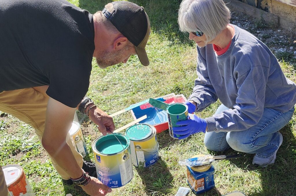 Scott Elliott of Adrian and Sally Dickson of Adrian refresh their paint while painting the new mural. (Photo by Erik Gable)