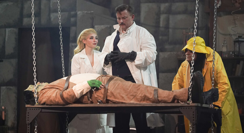 Payton Miller as Inga, Steve Antalek as Frederick Frankenstein, and Jordan Treger as Igor gather around as Frederick tries to animate the Monster, played by Micah Risher, in a scene from "Young Frankenstein" at the Croswell Opera House.