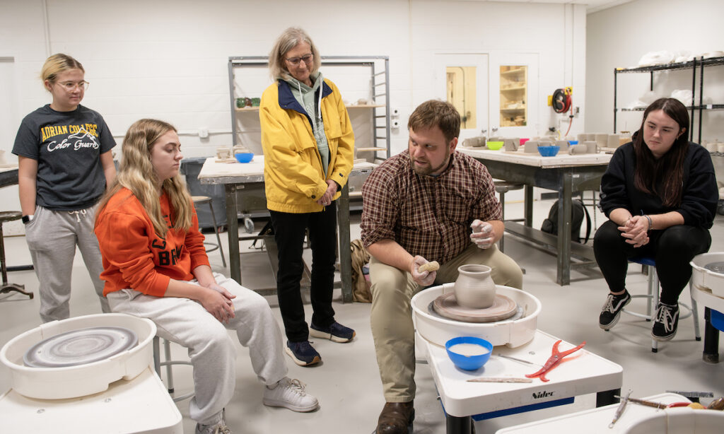 Adrian College art professor Travis Erxleben talks about throwing pottery with, from left to right, Summer Elkins, Ashlyn Vaculik, Stubnitz Foundation representative Christine McNaughton, and Tabitha Nelson.