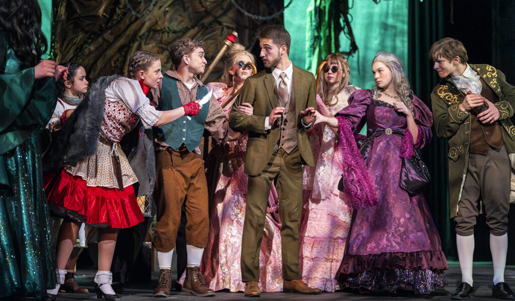 An angry mob of fairy-tale characters surrounds the narrator, Tyler Condon (Adrian High School), in the Croswell Opera House's all-area high school production of "Into the Woods." From left to right are Savanah Hernandez (Liberty Center High School) as the Baker's Wife, Ella Flumignan (Adrian High School) as Little Red Ridinghood, AJ Landingham (homeschool, Carleton) as Jack, Brenna Gifford and Amellia Bowman (both Adrian High School) as Cinderella's stepsisters, Amelia Martinal (Lenawee Christian School) as Cinderella's stepmother, and Alex Goetz (Blissfield High School) as Cinderella's father.