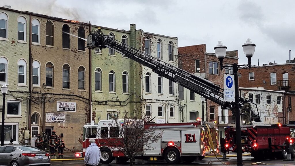 At about 6:20 p.m., a Madison Township aerial truck attacks the fire through a rear window of 121 W. Maumee St. At the same time, the Adrian Fire Department was working the front of the building.