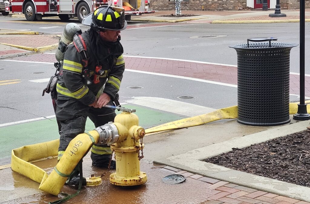 A Tecumseh firefighter starts water flowing from a hydrant at the corner of Main and Maumee streets at about 6:30 p.m. Saturday.