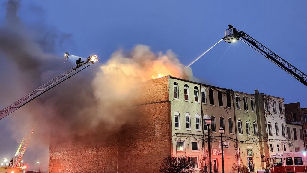 Firefighters pour water onto the roof while fighting the West Maumee Street fire shortly before 8 p.m. on Saturday.