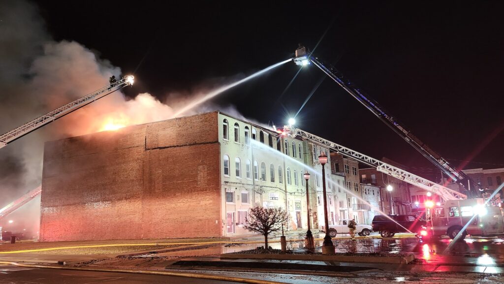 Firefighters pour water onto the roof from aerial trucks while others attack the fire through windows from the ground shortly before 8:45 p.m. Saturday.