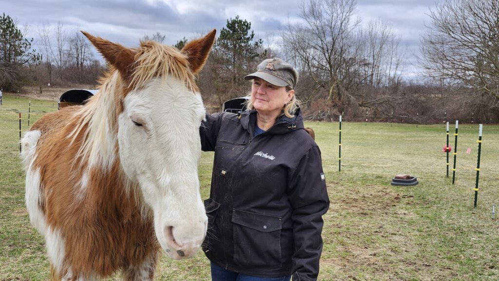 Michelle Wild stands with G.W., one of the horses who lives at Wild Acres Horse Rescue near Britton. Wild founded the rescue in 2021, and it’s been at its current location since May 2023. (Photo by Erik Gable)
