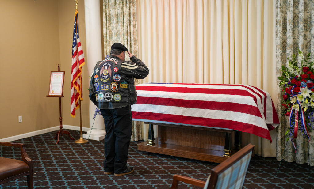 A member of the American Legion Riders salutes Staff Sgt. Ralph Mourer as he lies in state at Wagley Funeral Home in Adrian on May 19. (Photo by Lad Strayer)