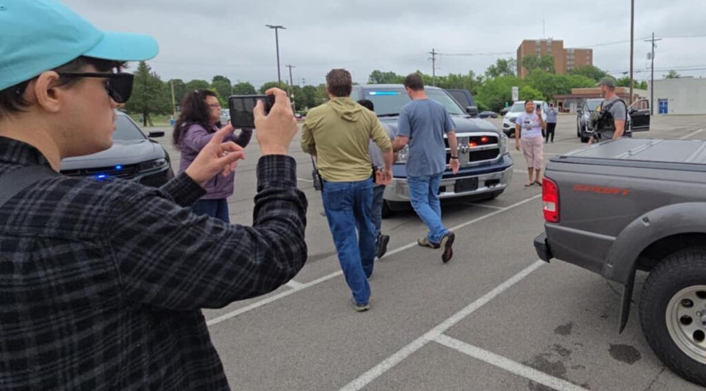 Federal agents take a man to their vehicle after handcuffing him in the parking lot across from Comstock Park on June 14.