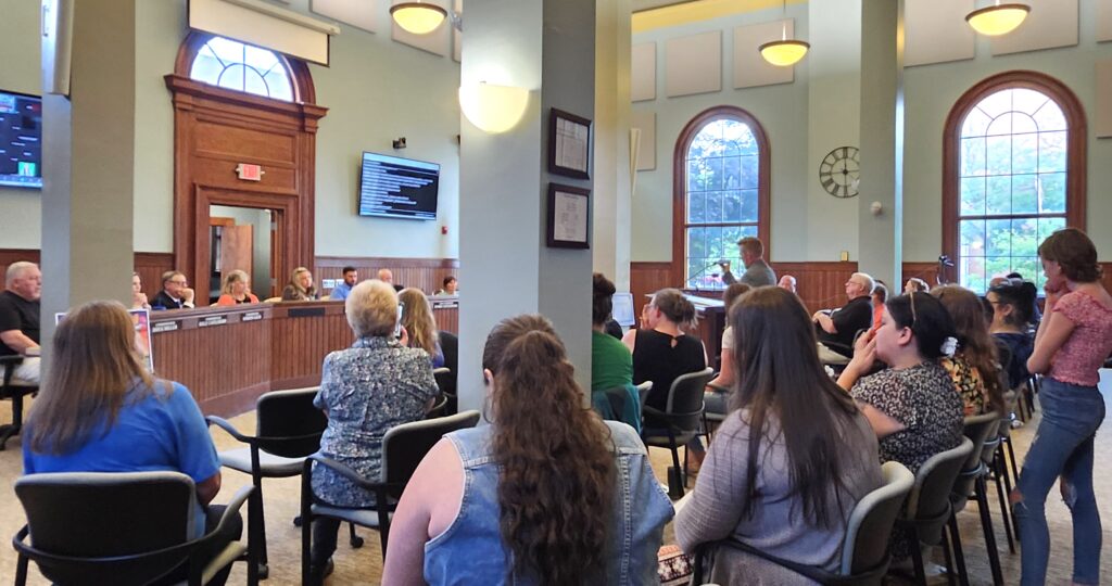 Ben Moorman of Adrian holds up his phone during the June 16 Adrian City Commission meeting to play a recording of family members reacting to an immigration arrest that occurred on June 14 in the parking lot across from Comstock Park.