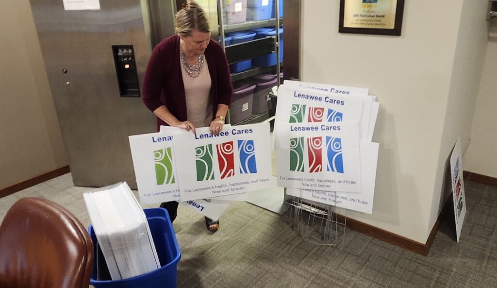 Kirsten Stiver, communications and engagement manager for the Lenawee Community Foundation, takes Lenawee Cares signs out of storage that will be displayed at organizations funded by the campaign during the 2024-25 giving cycle.