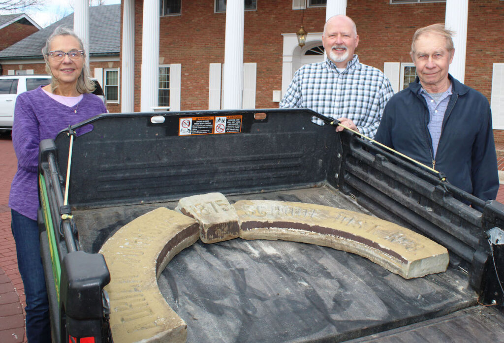 Mary Alice Thompson, Gleaner Life Insurance Society president and CEO Todd Warner, and Melvin Snyder are shown with the three recovered concrete pieces that stood above the entrance of Maynard School on Hamilton Highway. The pieces read “Adrian Township” and “School Dist. No. 8” on the left and right, and “1875” on the keystone. (Gleaner Life photo)