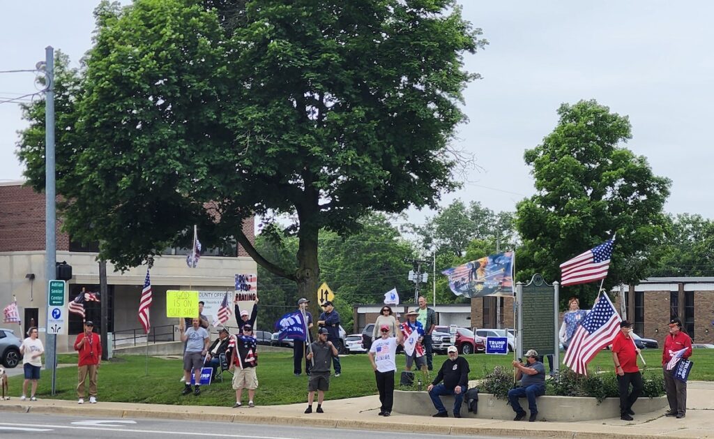 Supporters of President Trump carry signs reading "Don't stop praying" and "God is on our side" on June 14 in front of the Lenawee County Courthouse.