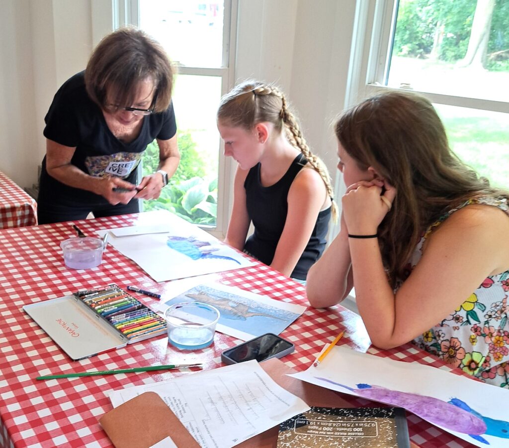 Jean Lash, founder of Manitou Beach Creative Corner, helps Laney Robidoux of Addison with her turtle as Ava Renner, also of Addison, looks on.