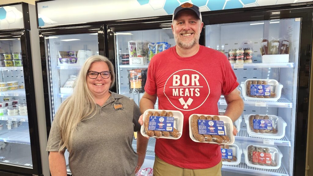 Gwynne Marks of Marks Trading Company and Bryan McEldowney of BOR Meats show some of the artisan sausages that the store started carrying at the end of June. Both companies have ties to Launch Lenawee and the Adrian Armory Makerspace Kitchen in Adrian. (Photo by Erik Gable)