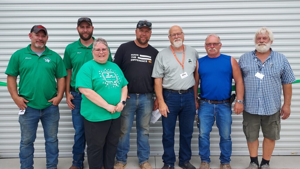 Shane Morse, Bryce Downard, Janelle Stewart, Ben Downard, Chris Downard, Brad Williams, and Marc Rising are pictured at the dedication of the new 4H show barn at the Lenawee County Fair and Event Grounds. (Photo by Julie C. Clemes)