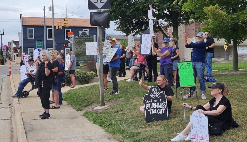 Protesters wave to passing cars during a "die-in" on Aug. 23 in Adrian.