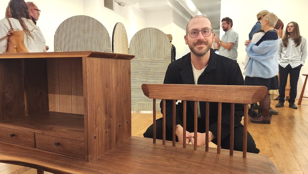 Zack Fealk poses with "Sit and Listen," a piece he made that is part of the Sam Beauford Woodworking Institute's show at the Ann Arbor Art Center gallery.