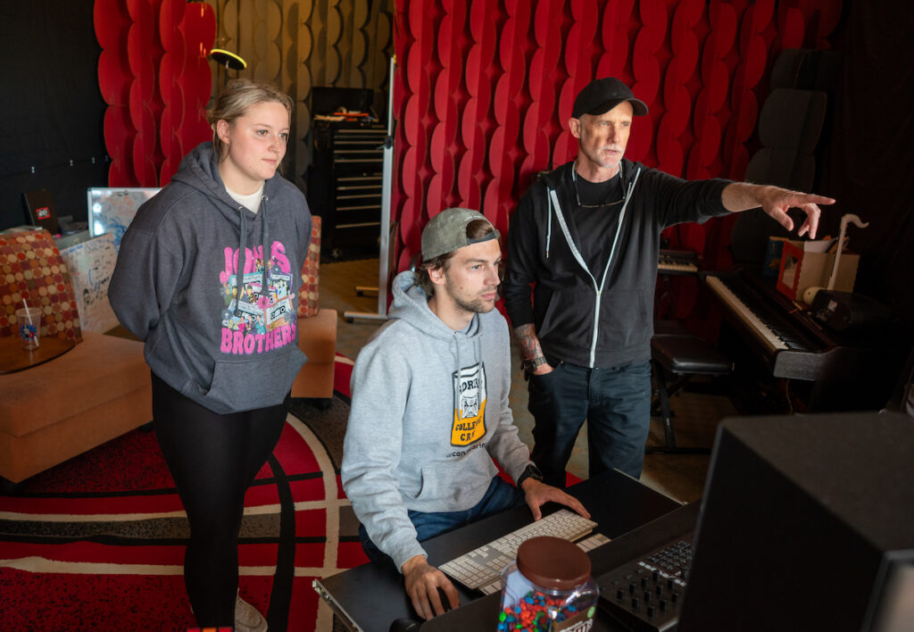 Maelynn Moffitt and Dylan Cumberland, both Adrian College students, work on recording a song they composed and that they are now turning into a midterm project. They are pictured here working with Pete Bishop, founder of Above Pete’s Garage. The nonprofit musical organization, which did indeed start above Bishop’s garage as the name suggests, provides studio space where people of all ages can learn how to play instruments, hone their songwriting and singing skills, get their music recorded, and use the latest technologies in audio and video production. (Photo by Lad Strayer)