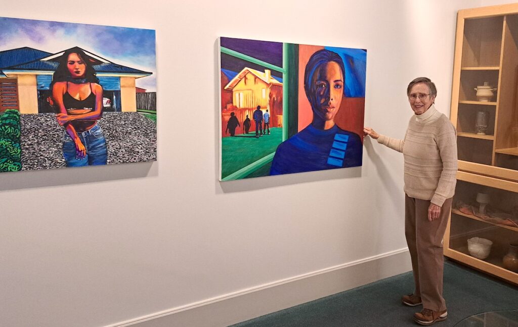 INAI at Madden Gallery coordinator Sister Sue Schreiber, OP, is pictured with an acrylic painting by Doris DeNudt that’s part of the INAI Gallery’s first exhibit in its new space. “Engage: The Art of Women” runs from April 11 to Aug. 2. (Photo by Arlene Bachanov)