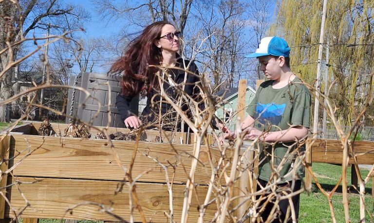 Christie Boxer and her son Benjamin are pictured recently at the community garden on George Street. A community planting day is scheduled for May 23 at the garden, which was started by the Boxer family with help from Adrian Parks and Recreation, and maintained by community volunteers. (Photo by Erik Gable)