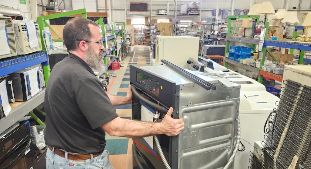 Anthony Sacco, director of the Habitat for Humanity ReStore, moves an oven into place at the store. The ReStore, which marks its 20th anniversary this year, is now open until 6 p.m. four days a week. (Photo by Erik Gable)