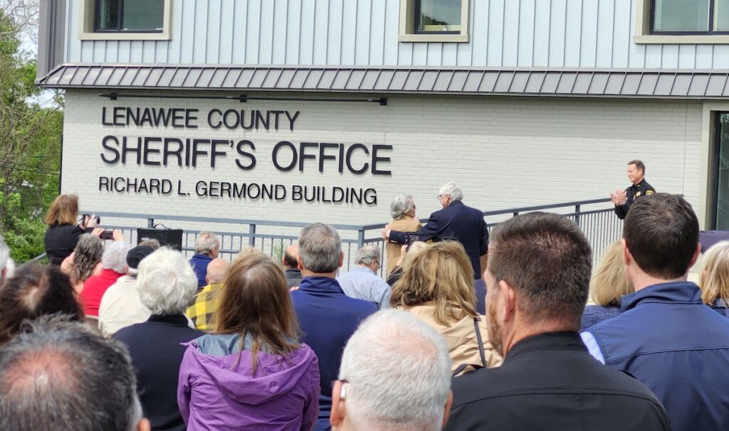Carol Germond and Lenawee County Commission chairman Jim Van Doren are pictured immediately after unveiling the name of Germond’s late husband, Sheriff Richard Germond, on the Lenawee County Sheriff’s Office building. The building was formally named for Germond on May 22. (Photo by Erik Gable)