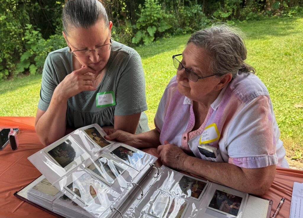 Belinda Carlson Lolley and her mom, Vickie Carlson, leaf through a photo album at the Adrian A&W Reunion in Burr Ponds Park.