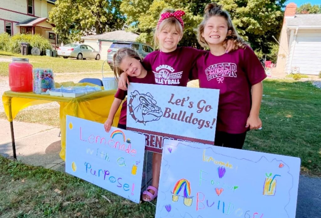 Sisters Navy, Blake and Ezri Hall are pictured at the lemonade stand they ran on July 23 to fund school supplies at the community’s Back-to-School Bash. 