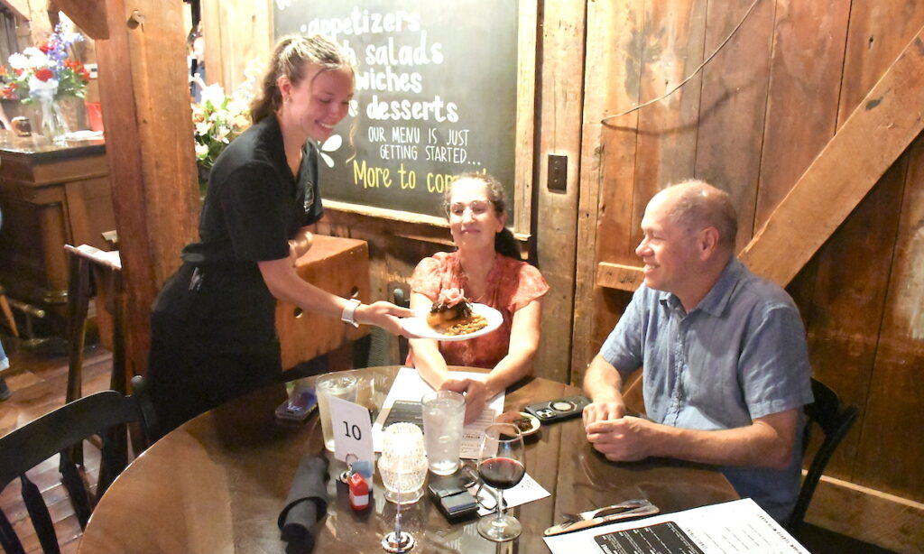 Ellie Sayler delivers an appetizer to Julie and Rick Hedrick at The Stable’s soft opening on July 17. (Photos by Erik Gable)
