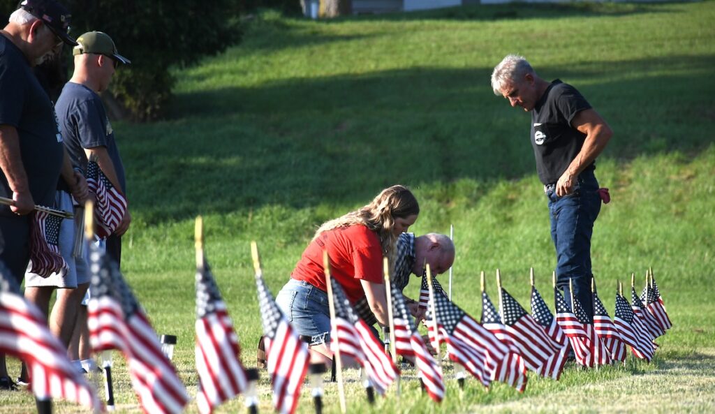 Volunteers plant a second row of flags in the ground on Sept. 2 at Clayton's village park, part of a project to place 22 flags every day throughout the month of September to recognize the problem of veterans dying by suicide. (Photo by Erik Gable)